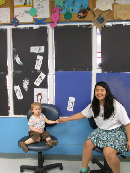 Hong and a young Discovery lab participant bond next to carbon footprint reduction pledges.