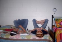 two people on a bed with legs up on the wall