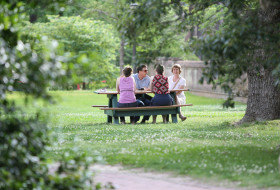 Family sitting at a picnic table on campus