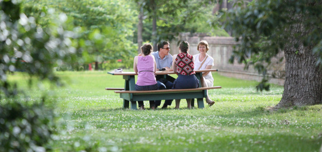 Family sitting at a picnic table on campus