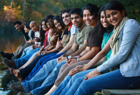 diverse group of students sit on dock at Lake Matoaka