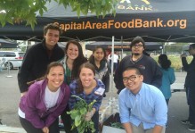 a group poses in front of a tent that reads "Capital Area Food Bank.org"