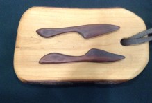 a wooden cheeseboard with wooden knives