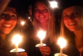 a student holding candles with 2 other students
