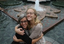 a student hugs her mom in front of a fountain