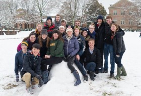 Smiling students sitting on a pile of snow