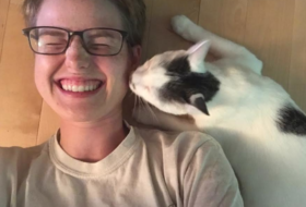 black and white kitten gives smiling girl a peck on the cheek