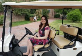 Women smiles posing for picture in the front seat of a white golf cart