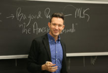 a professor lecturing in front of a chalk board