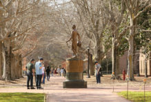 passers by stop in front of Monroe statue on old campus