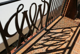 Cypher shadow from wrought iron gate on bricks