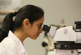 Female student looking into microscope