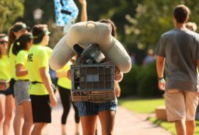 Student carrying a tall stack of dorm supplies during Move-In