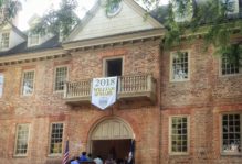 Students walk through the wren building during convocation 2018. The class banner hangs from the balcony.