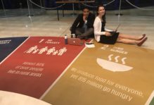 Lauren Hobbs and Josh Panganiban sitting on a floor with a large graphical chart