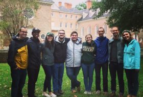 a group of 9 W&M almuni posing as a group in front of the Wren Building at Homecoming & Reunion Weekend 2018