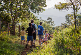 Students Allie Cooper, Noah Scruggs and Sophie Harris walk with a group of Guatemalan children near a rural community.