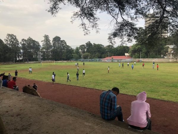 students playing a game of soccer on a field with a few onlookers