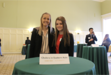 Two students standing at a draped cocktail table with a placard that reads Cholera in Eastern Asia