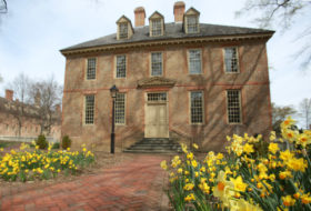 Historic brick building in early spring with bright yellow daffodils in bloom in the foreground.