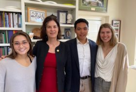 Four people posed smiling in an office.