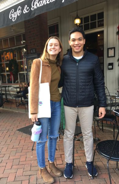 Two students posed and smiling out front of Aroma's cafe.