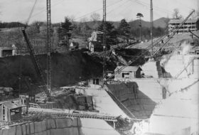 Black and white photo of closely neighboring rock quarries with small buildings, tracks and cranes around their perimeters