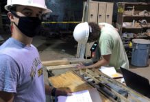 Two W&M researchers in masks and hard hats examining rock cores.