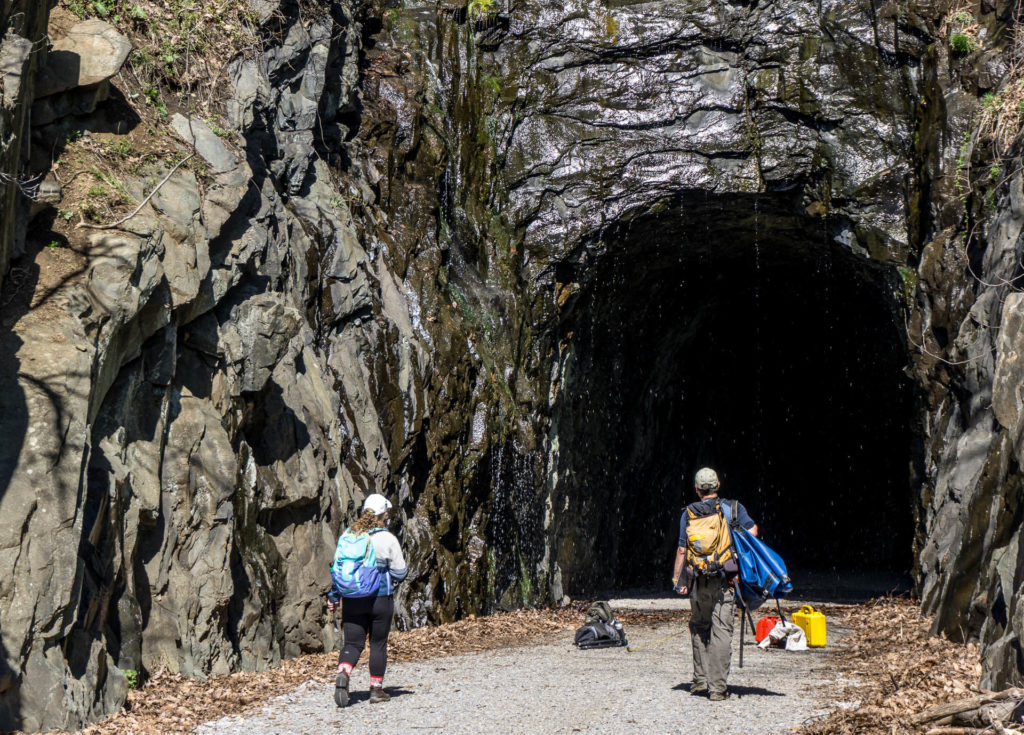 Two W&M geologists with backpacks and in hiking gear, entering the Blue Ridge Tunnel.