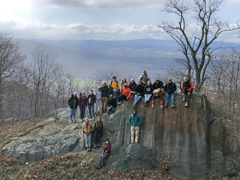 Students standing on a big rock in the mountains