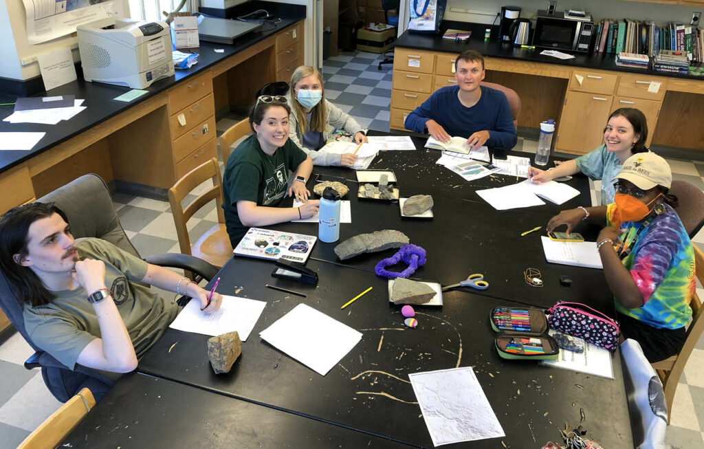 Six students around a large work table in a geology lab