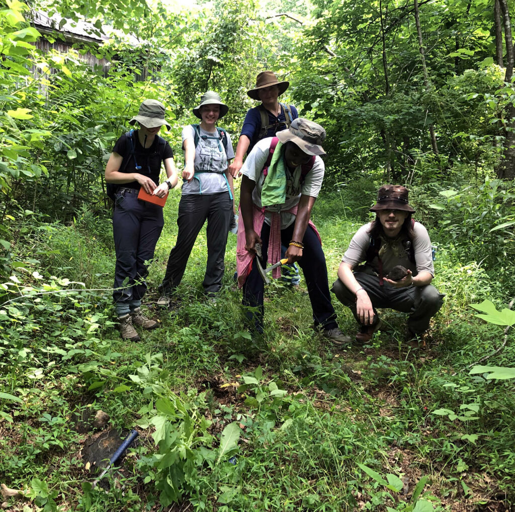 Five geology students in the woods searching for outcrop