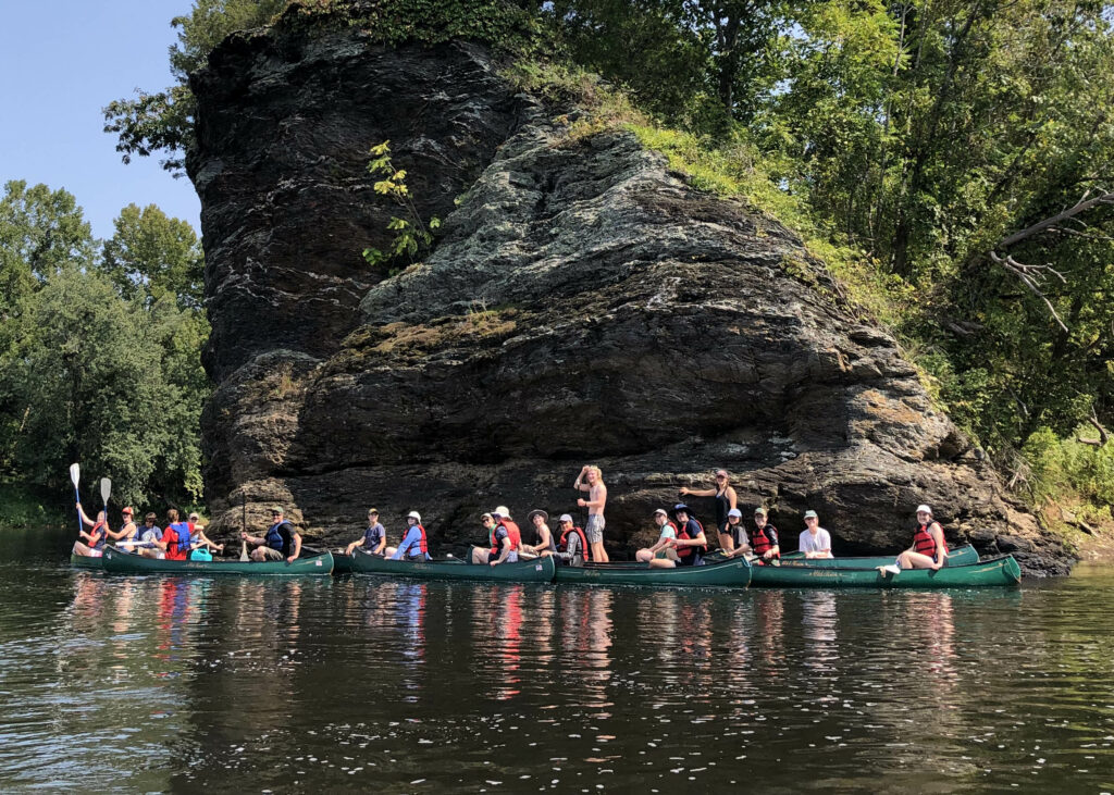 Students in canoes in front of an outcrop at Rock Island