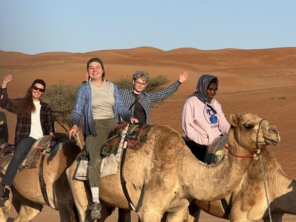 Students riding camels in the desert