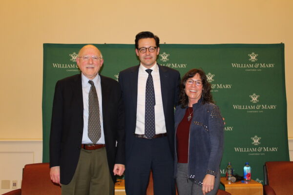 Three people posed in front of a William & Mary backdrop