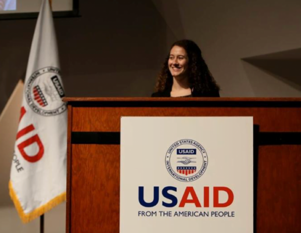 Stern smiling at a large USAID podium and flag